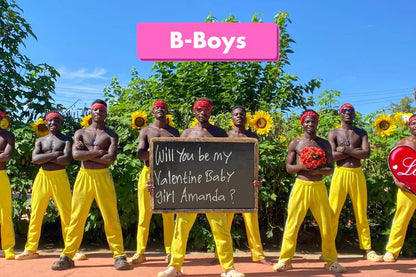 The African B-Boys team wearing yellow pants and holding a heart-themed Valentine's message board